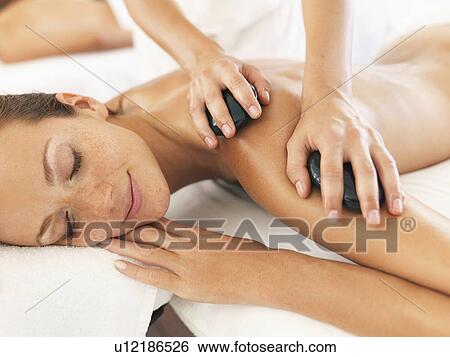 Stock Photograph - Woman relaxing while getting stone massage. Fotosearch