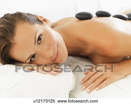 Stock Photography - Woman relaxing while getting stone massage. Fotosearch