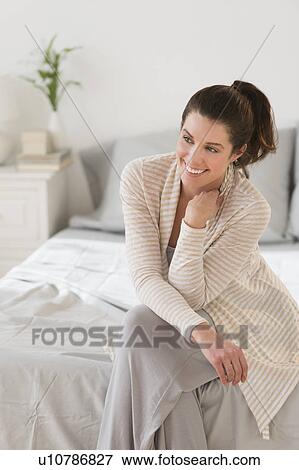 Stock Photo - Woman sitting on bed. Fotosearch