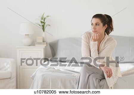 Stock Photography - Woman sitting on bed. Fotosearch
