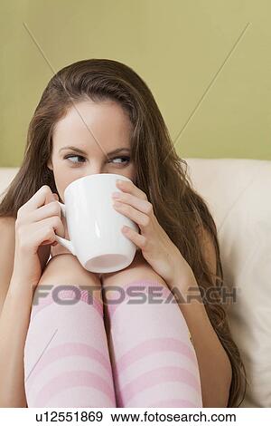Woman sitting on sofa and holding mug View Large Photo Image Stock Photo - Woman sitting on sofa and holding mug. Fotosearch
