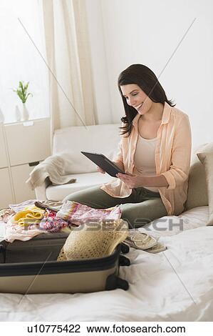 Woman using digital tablet while packing suitcase View Large Photo Image Stock Image - Woman using digital tablet while packing suitcase. Fotosearch