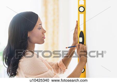 Stock Image - Woman using spirit level. Fotosearch