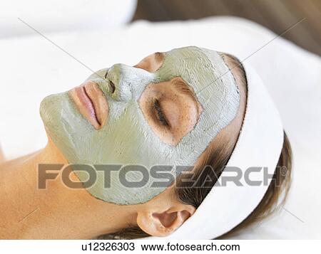 Stock Image - Woman with face mask relaxing in spa. Fotosearch