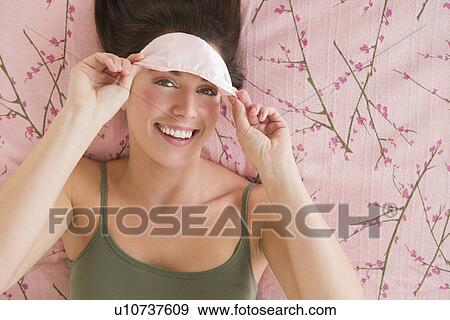 Stock Photo - Woman with sleep mask lying on bed . Fotosearch