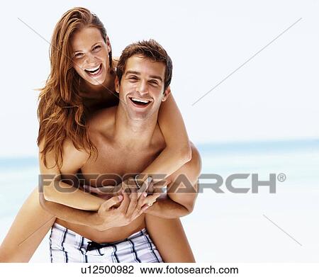 Stock Image - Young attractive couple enjoying summer holiday on beach. Fotosearch