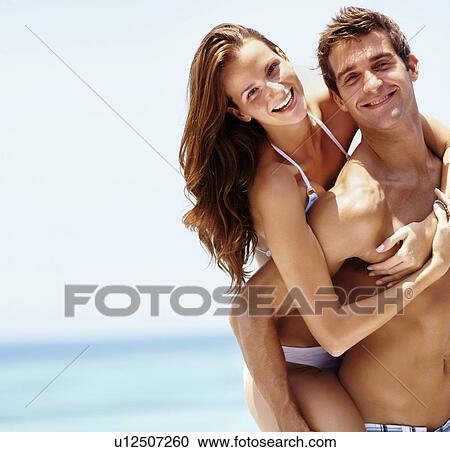 Young attractive couple enjoying summer holiday on beach View Large Photo Image Stock Image - Young attractive couple enjoying summer holiday on beach. Fotosearch