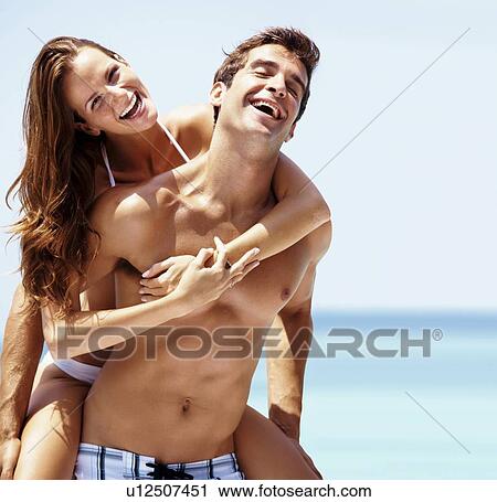 Young attractive couple enjoying summer holiday on beach View Large Photo Image Stock Image - Young attractive couple enjoying summer holiday on beach. Fotosearch