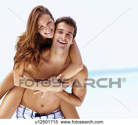 Stock Photography - Young attractive couple enjoying summer holiday on beach. Fotosearch