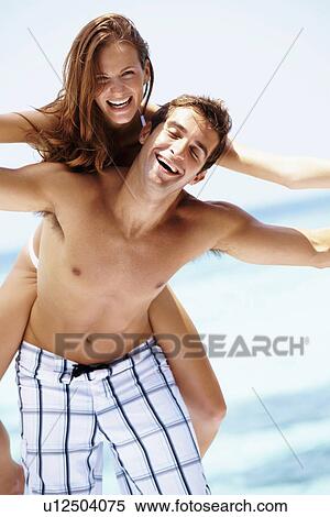 Stock Photography - Young attractive couple enjoying summer holiday on beach. Fotosearch