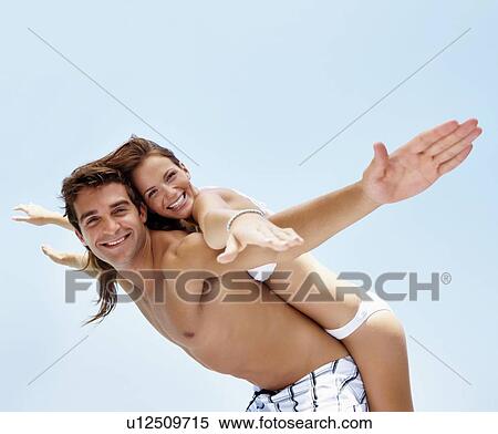 Stock Photography - Young attractive couple enjoying summer holiday on beach. Fotosearch