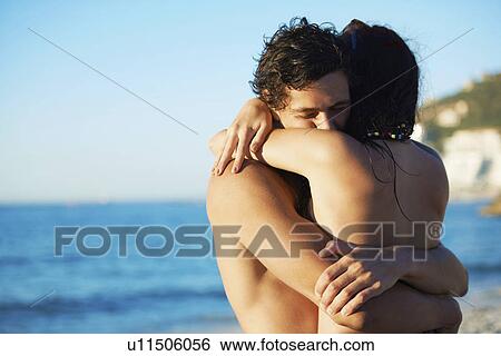Stock Photograph - Young couple hugging at beach. Fotosearch