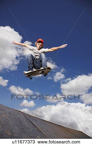 Stock Image - Young man on skateboard jumping. Fotosearch