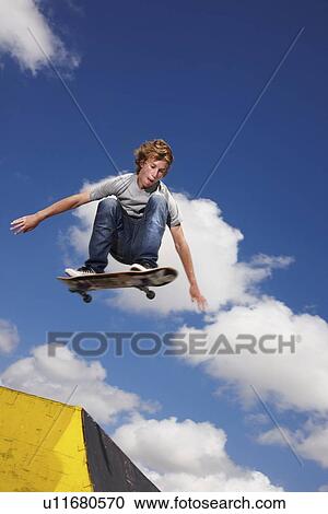 Young man on skateboard jumping View Large Photo Image Stock Image - Young man on skateboard jumping. Fotosearch