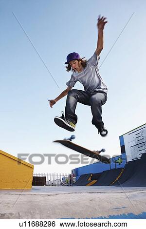 Stock Photograph - Young man on skateboard jumping. Fotosearch