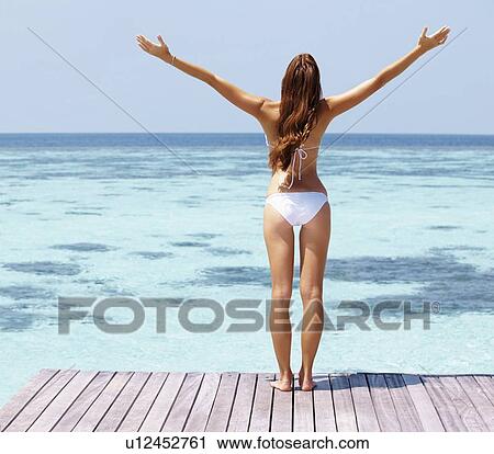 Young woman in bikini standing on jetty View Large Photo Image Stock Image - Young woman in bikini standing on jetty. Fotosearch