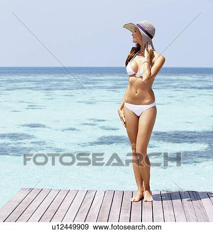 Young woman in bikini standing on jetty View Large Photo Image Stock Photo - Young woman in bikini standing on jetty. Fotosearch