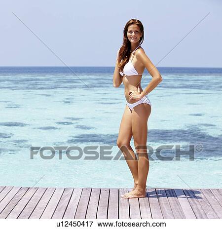 Young woman in bikini standing on jetty View Large Photo Image Stock Photo - Young woman in bikini standing on jetty. Fotosearch