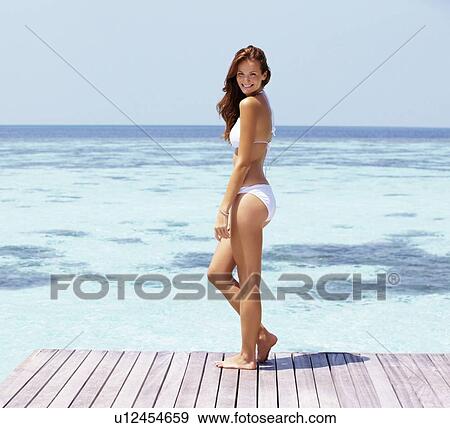 Young woman in bikini standing on jetty View Large Photo Image Stock Photo - Young woman in bikini standing on jetty. Fotosearch