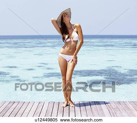 Young woman in bikini standing on jetty View Large Photo Image Stock Photography - Young woman in bikini standing on jetty. Fotosearch