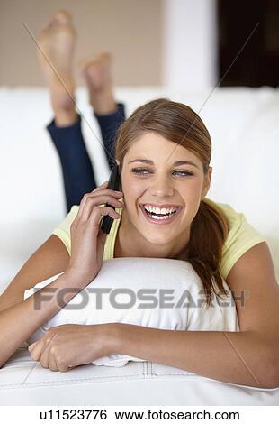 Young woman lying on bed and talking on phone View Large Photo Image Stock Photograph - Young woman lying on bed and talking on phone. Fotosearch