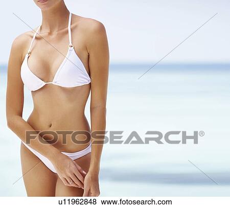 Stock Photo - Young woman wearing bikini, mid section. Fotosearch