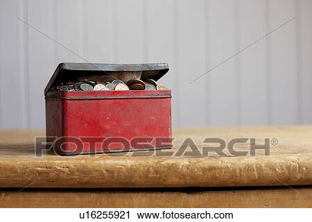 Stock Image - Antique tin full of money on desk. Fotosearch