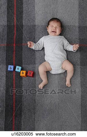 Stock Photography - Baby boy crying on bed. Fotosearch