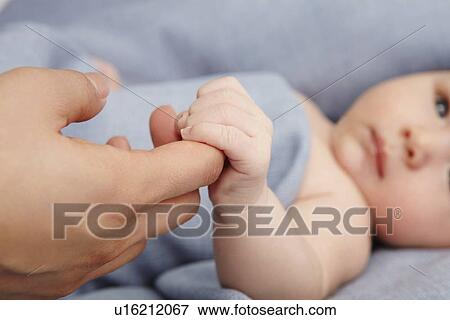 Baby boy holding mothers finger in bed View Large Photo Image Stock Photo - Baby boy holding mothers finger in bed. Fotosearch