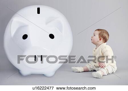 Baby girl examining large piggy bank View Large Photo Image Stock Photo - Baby girl examining large piggy bank. Fotosearch