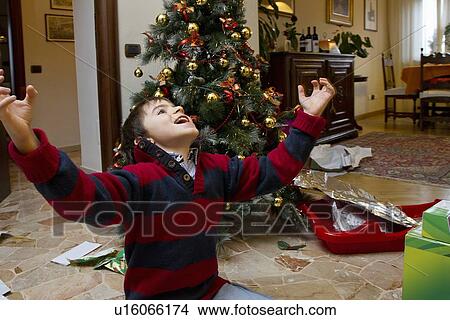 Boy cheering by Christmas tree View Large Photo Image Picture - Boy cheering by Christmas tree. Fotosearch