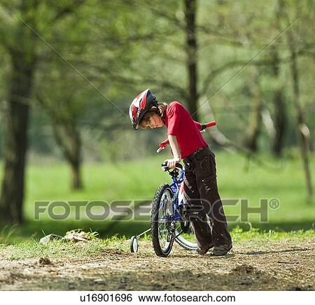 Boy climbing on bicycle in park View Large Photo Image Stock Photograph - Boy climbing on bicycle in park. Fotosearch