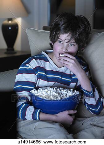 Boy eating popcorn in front of movie View Large Photo Image Stock Photograph - Boy eating popcorn in front of movie. Fotosearch