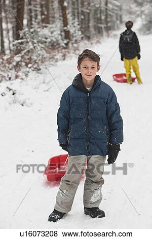 Boy holding sled on snowy slope View Large Photo Image Stock Photo - Boy holding sled on snowy slope. Fotosearch