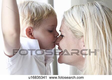 Stock Image - Boy kissing mother at window. Fotosearch