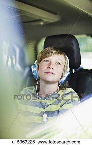 Boy listening to headphones in car View Large Photo Image Stock Photograph - Boy listening to headphones in car. Fotosearch