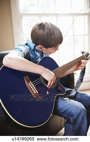 Boy playing guitar on sofa View Large Photo Image Stock Photo - Boy playing guitar on sofa. Fotosearch