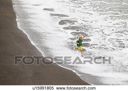 Stock Photography - Boy playing in waves on beach. Fotosearch