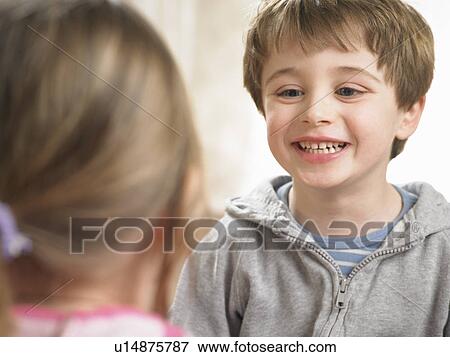 Boy smiling at girl indoors View Large Photo Image Stock Photo - Boy smiling at girl indoors. Fotosearch