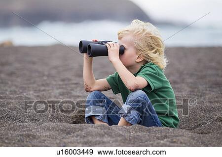 Stock Photo - Boy using binoculars on beach. Fotosearch