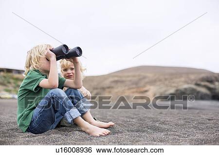 Stock Photograph - Boy using binoculars on beach. Fotosearch
