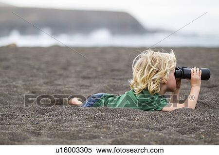 Stock Photography - Boy using binoculars on beach. Fotosearch