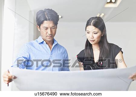 Stock Image - Business people reading blueprints. Fotosearch
