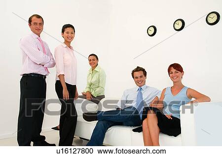 Stock Image - Business people smiling in lobby area. Fotosearch