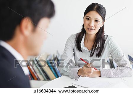 Picture - Business people talking at desk. Fotosearch