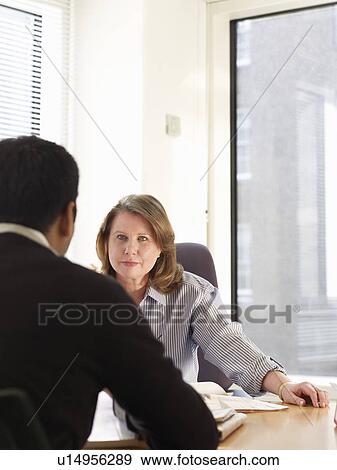 Stock Photo - Business people talking at desk. Fotosearch