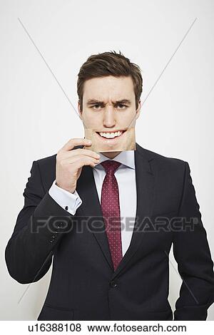 Businessman holding angry picture over his face View Large Photo Image Stock Photo - Businessman holding angry picture over his face. Fotosearch