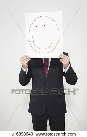 Businessman holding happy face over his face View Large Photo Image Stock Image - Businessman holding happy face over his face. Fotosearch