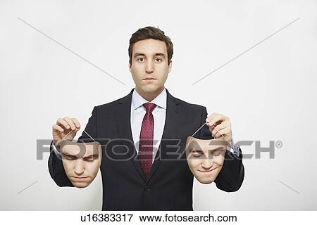 Stock Photo - Businessman holding masks. Fotosearch