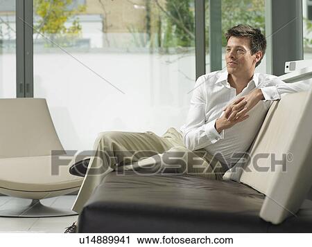 Businessman on sofa in office lobby View Large Photo Image Stock Image - Businessman on sofa in office lobby. Fotosearch